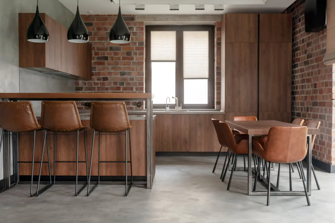 Kitchen with exposed brick on the wall and grey microcement on the floor